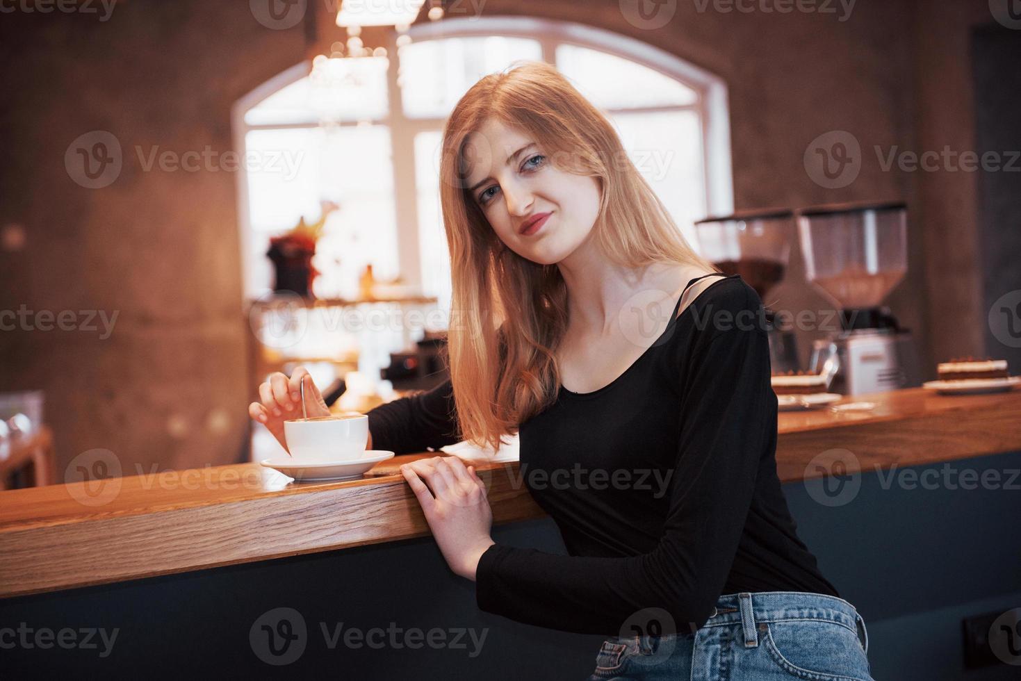 Bastante joven sentada en el café con una taza de té foto