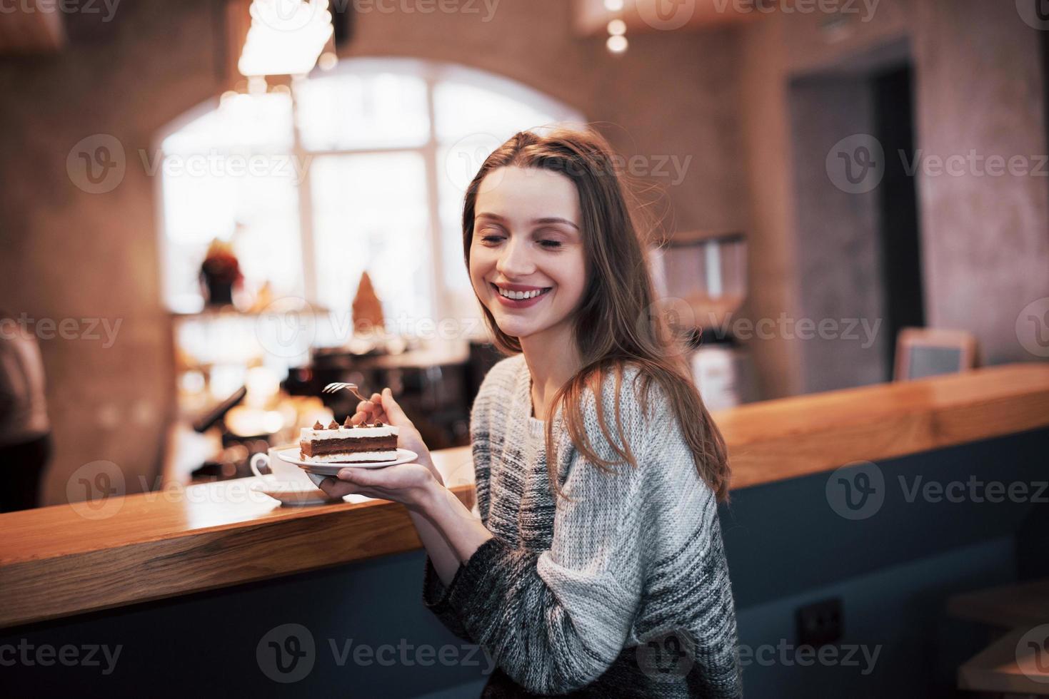 Happy smiling young woman using phone in a cafe. Beautiful girl in trendy spring colors photo