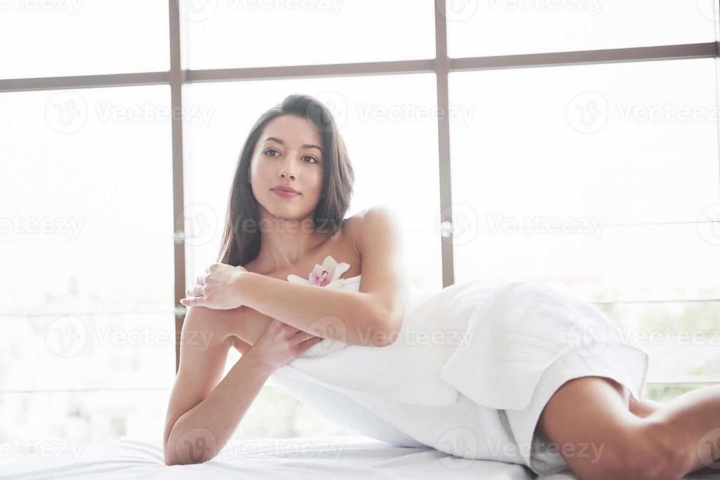 Hermosa joven relajándose en una toalla con una flor de orquídea aislado sobre un fondo blanco. foto