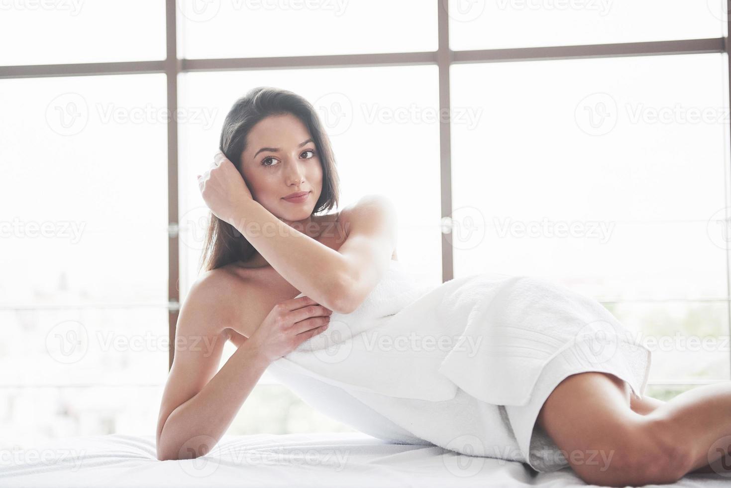 Hermosa joven relajándose en una toalla con una flor de orquídea aislado sobre un fondo blanco. foto