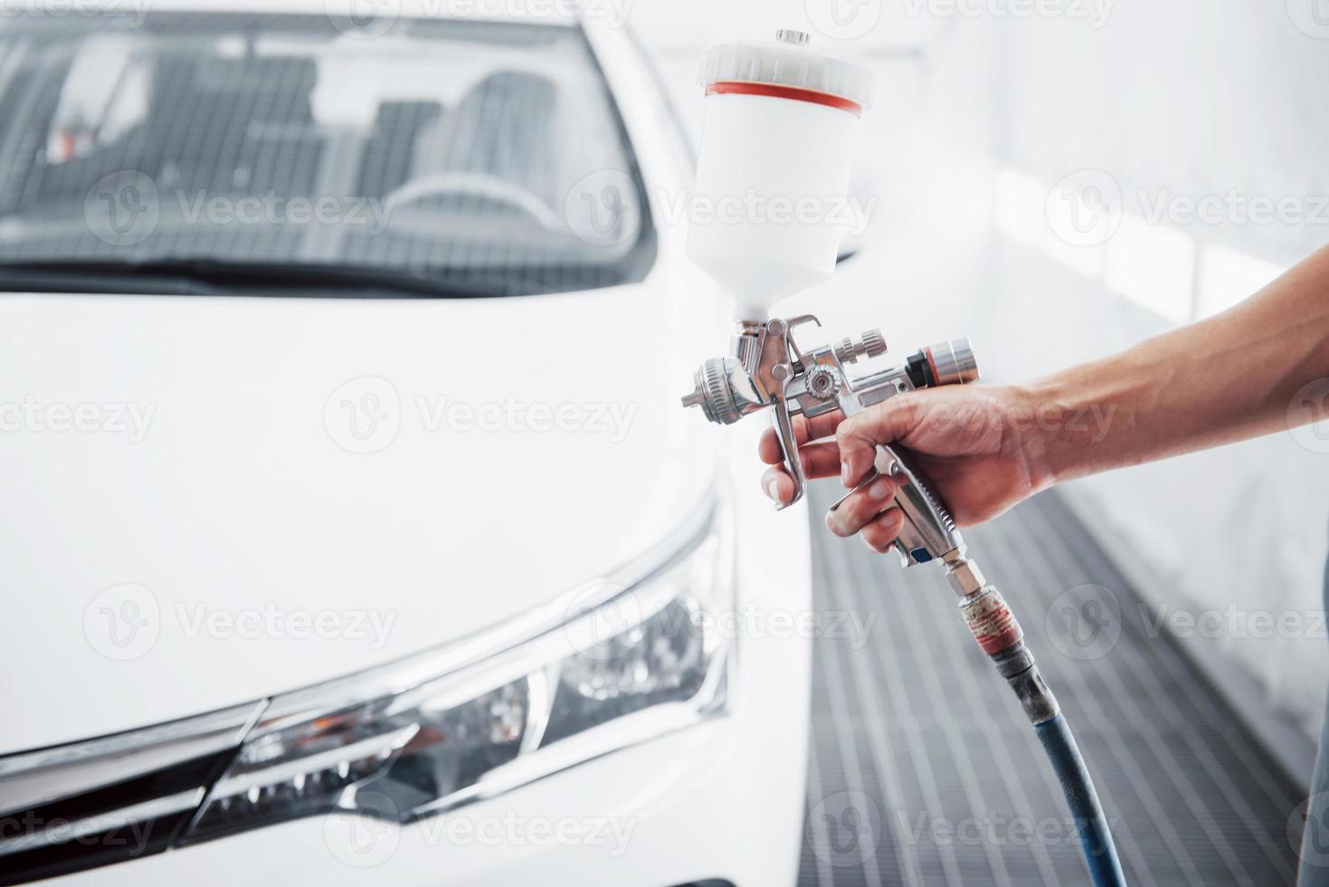 gun with paint in the hands of a man to paint a car photo