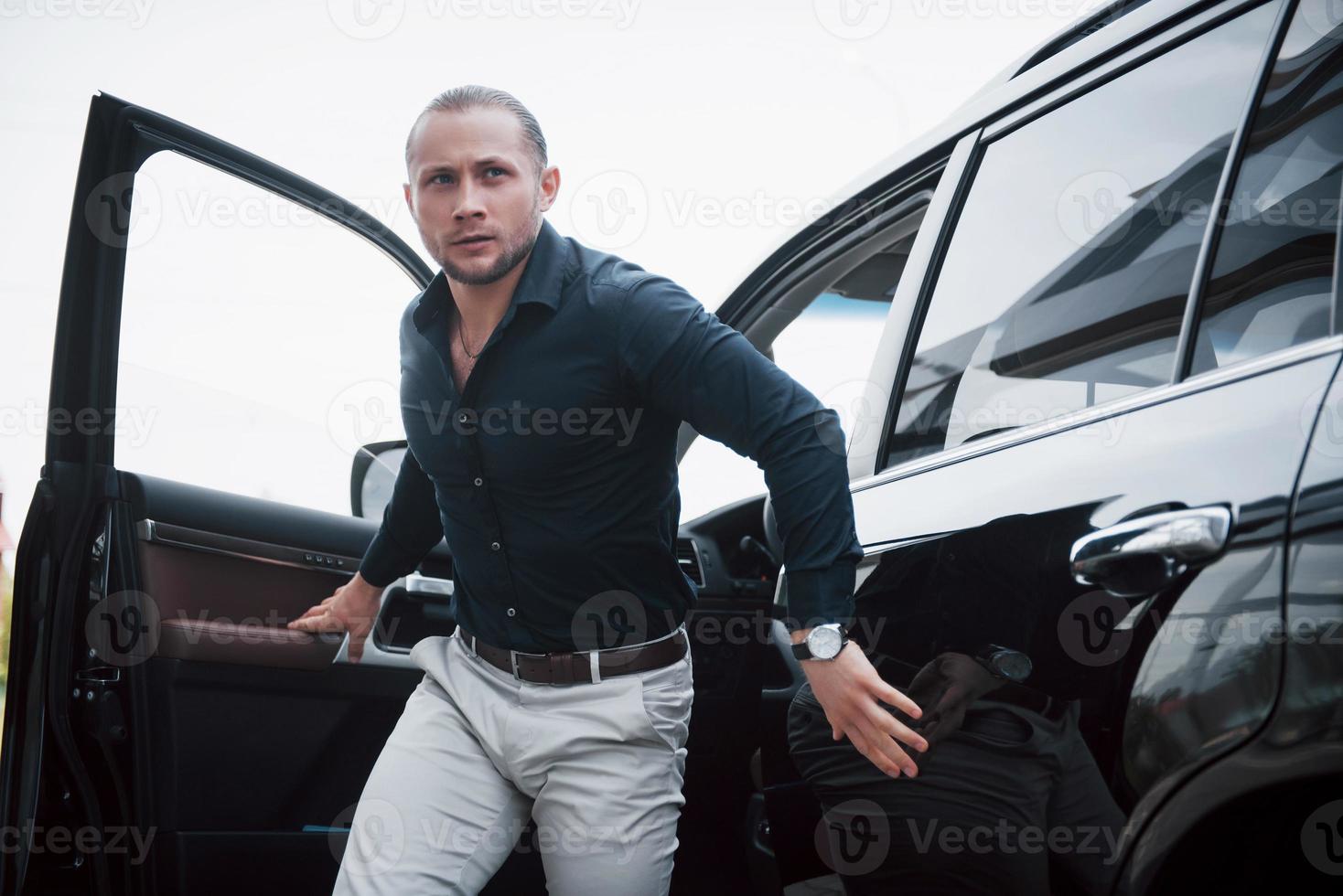 retrato de un joven guardaespaldas cerca del coche. el realiza un trabajo peligroso foto