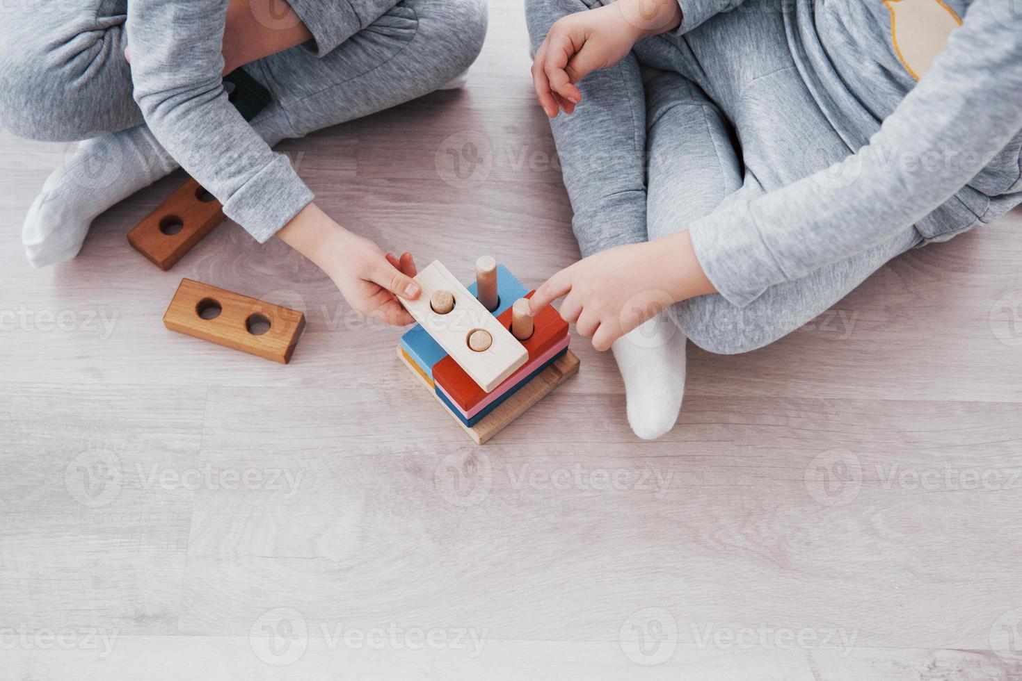 Los niños juegan con un diseñador de juguetes en el piso de la habitación de los niños. dos niños jugando con bloques de colores. juegos educativos de jardín de infantes foto