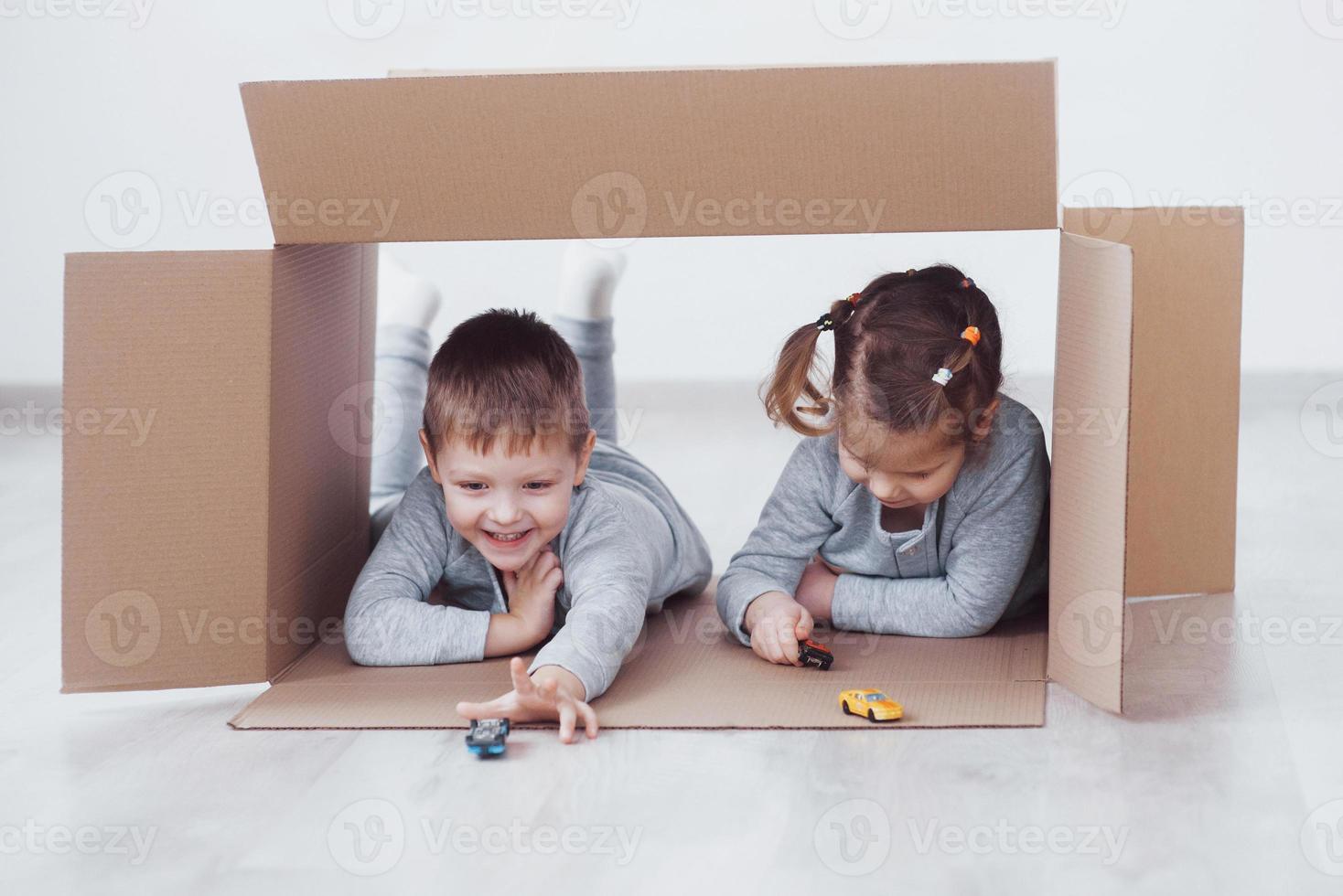 Hermano y hermana infantil jugando en cajas de cartón en la guardería foto