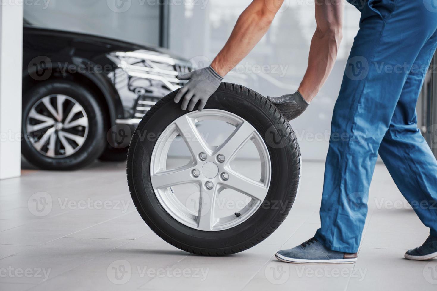 Mechanic holding a tire tire at the repair garage. replacement of winter and summer tires photo
