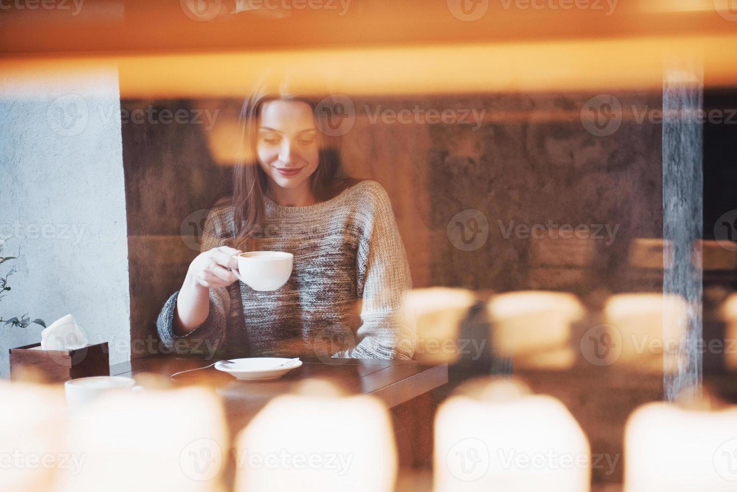 pretty young woman sitting in the cafe with a cup of tea photo
