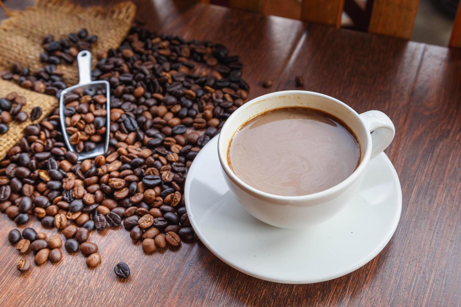 cup of coffee and coffee beans in a sack on  Brown background, top view photo