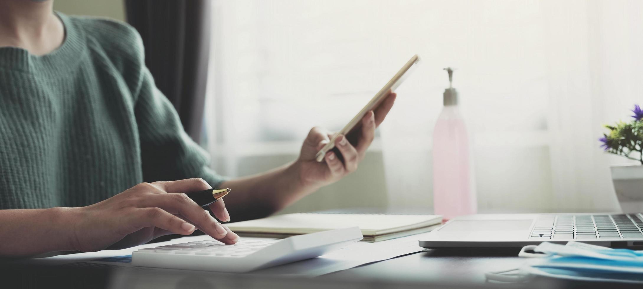 concepto de contabilidad, impuestos y finanzas - mujer con teléfono inteligente y calculadora con máscara médica protectora facial para protegerse de enfermedades virales en el hogar. foto