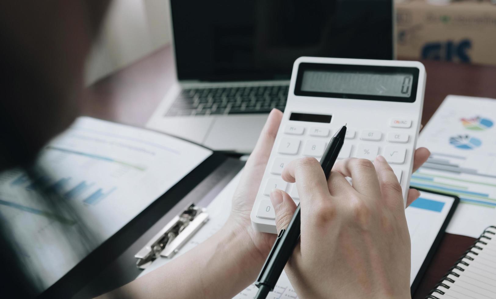 Close up Business woman using calculator and laptop for do math finance on wooden desk in office and business working background, tax, accounting, statistics and analytic research concept photo