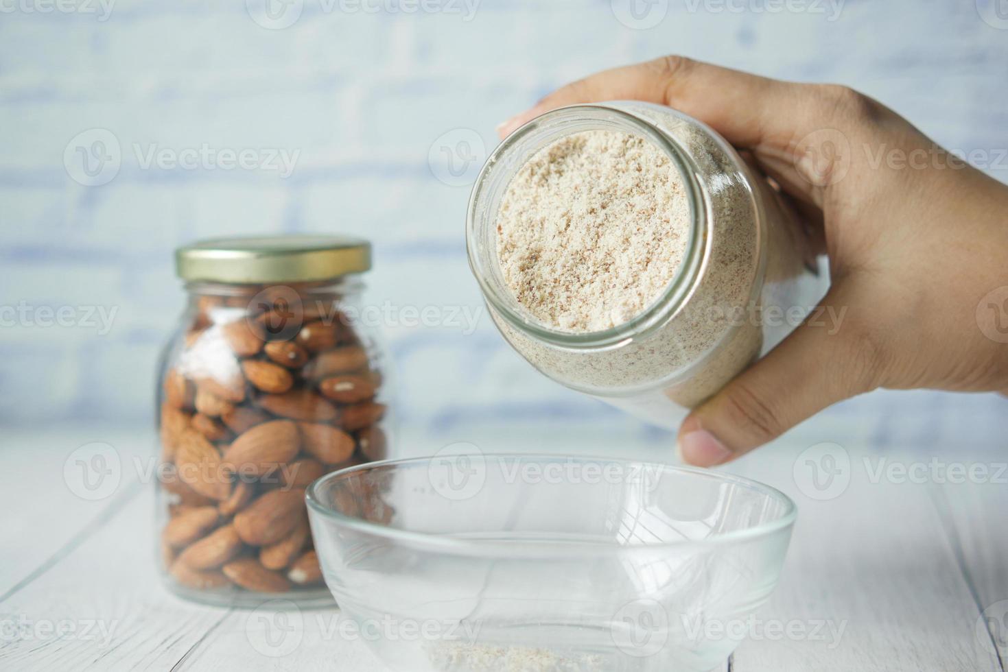 polvo de almendras y almendras en un frasco sobre la mesa, foto