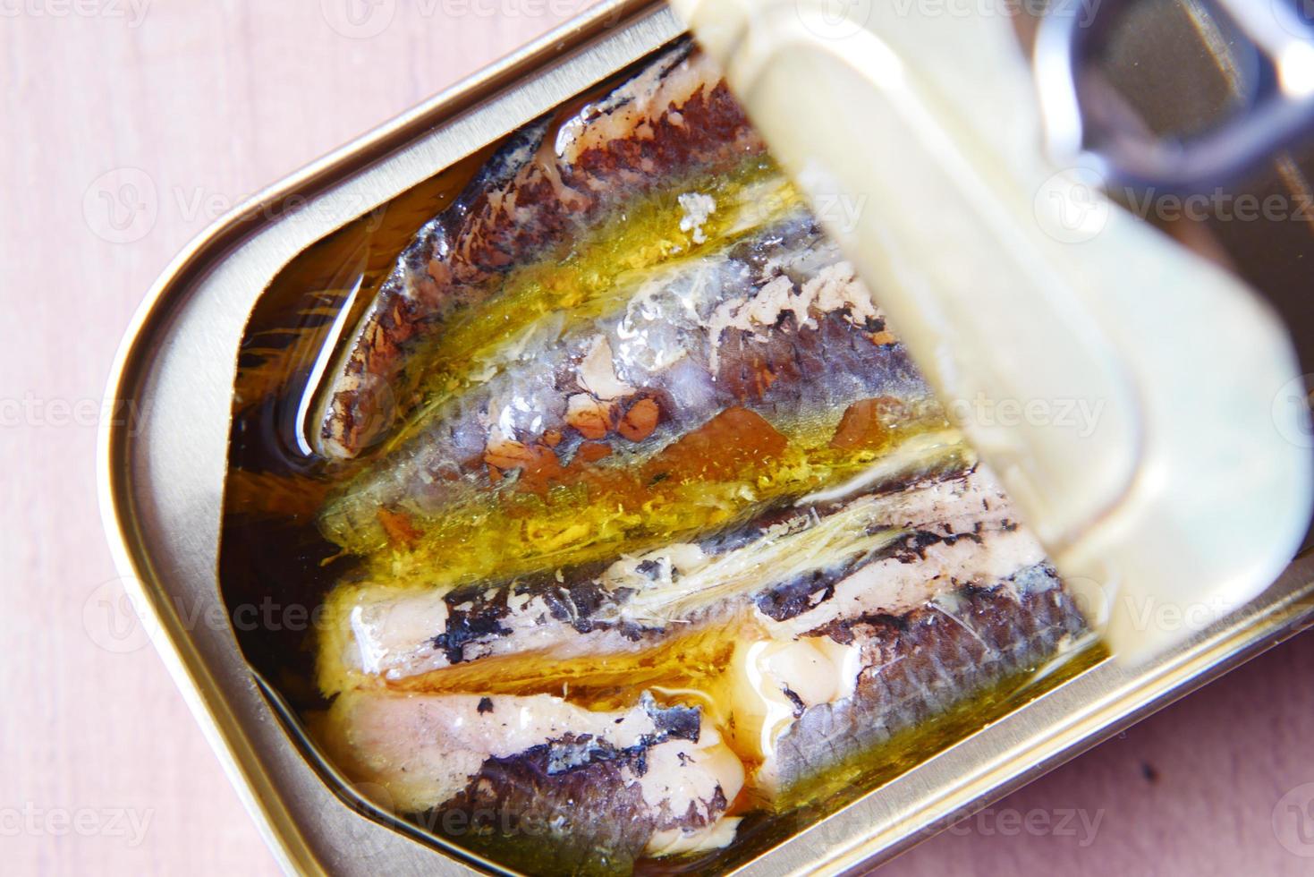 open tin of sardines on white tiles background. photo