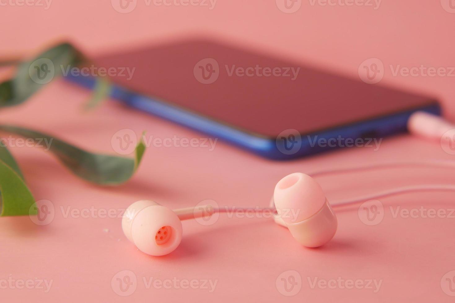 smart phone with empty screen, earphone on pink background photo