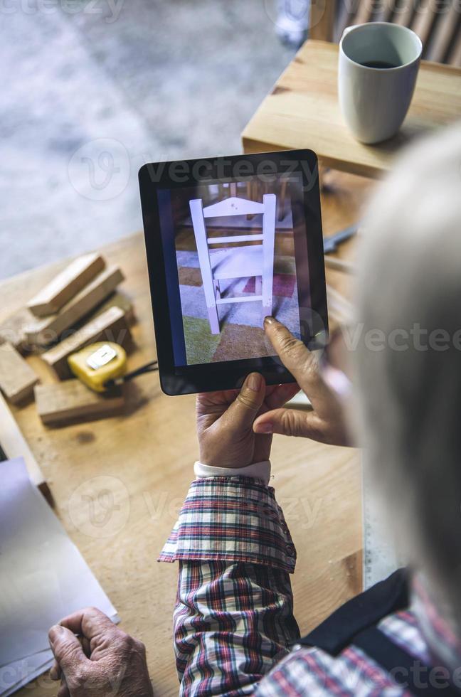 Mujer mayor irreconocible en una carpintería buscando tablet foto