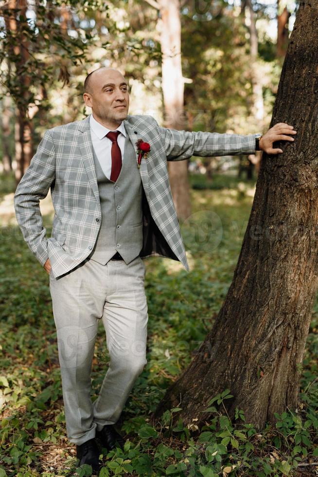 Chico calvo con una chaqueta gris sobre un fondo de árbol foto