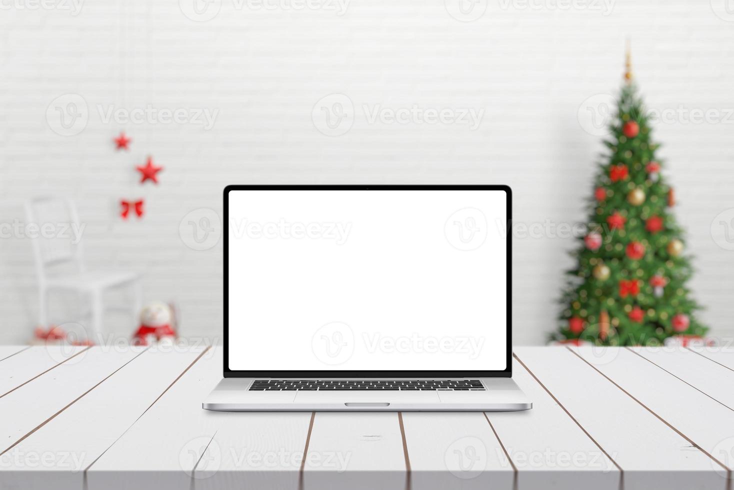 Maqueta de ordenador portátil en deskj de madera blanca con adornos navideños en segundo plano. foto