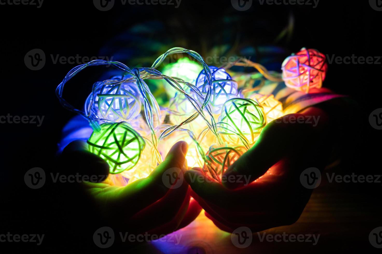 kid holding a garland in hands, glowing with colorful multicolored lights at night photo