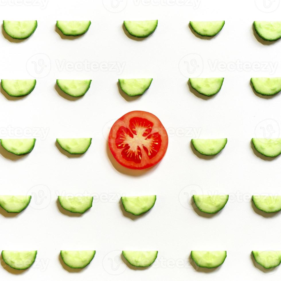 repeating pattern of sliced semicircles of fresh raw vegetable cucumbers for salad and tomato photo