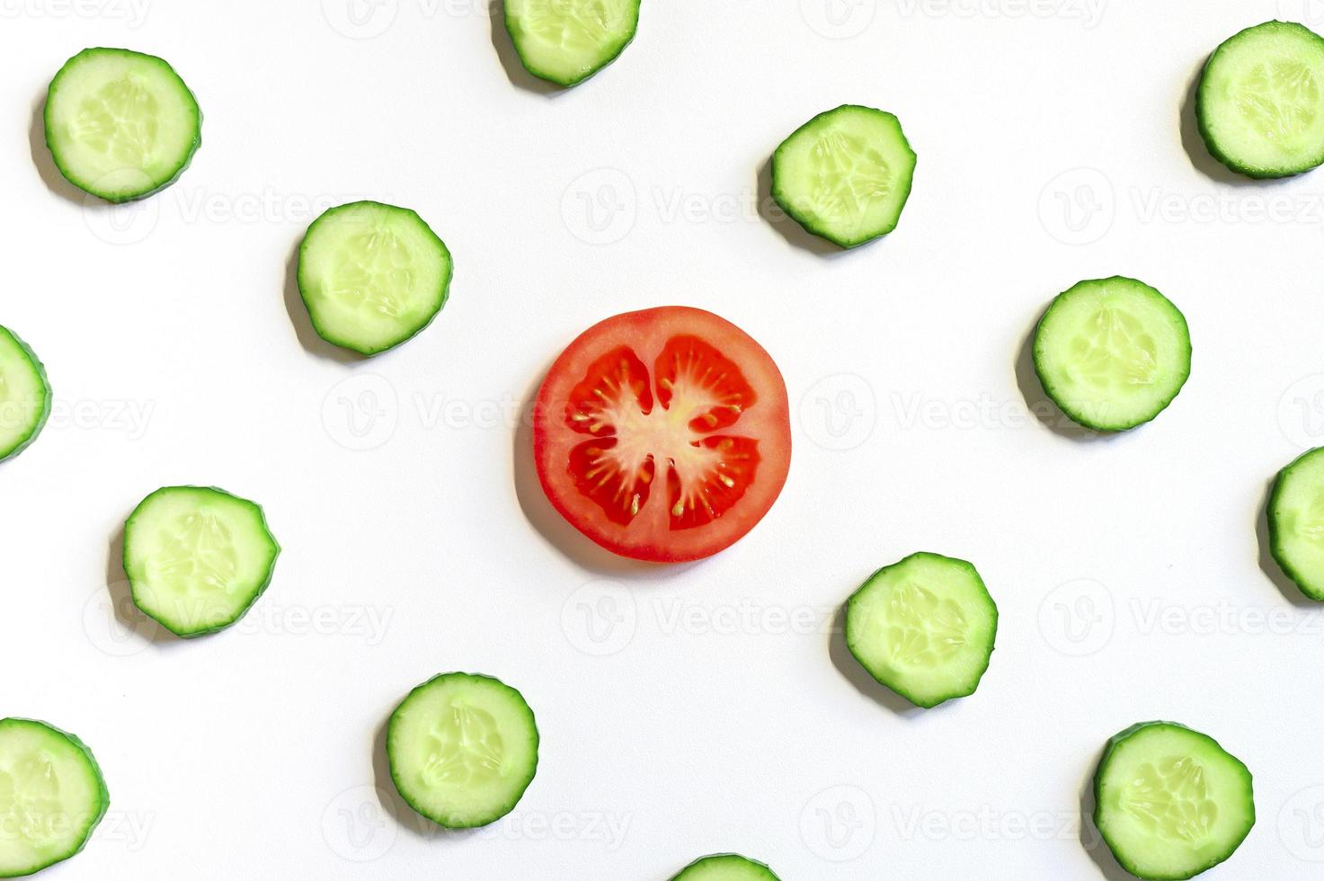 Patrón repetitivo de semicírculos en rodajas de pepinos vegetales crudos frescos para ensalada y una rodaja de tomate foto