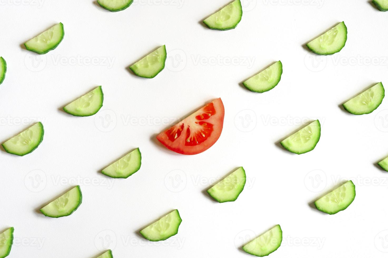 Patrón repetitivo de semicírculos en rodajas de pepinos vegetales crudos frescos para ensalada y una rodaja de tomate foto