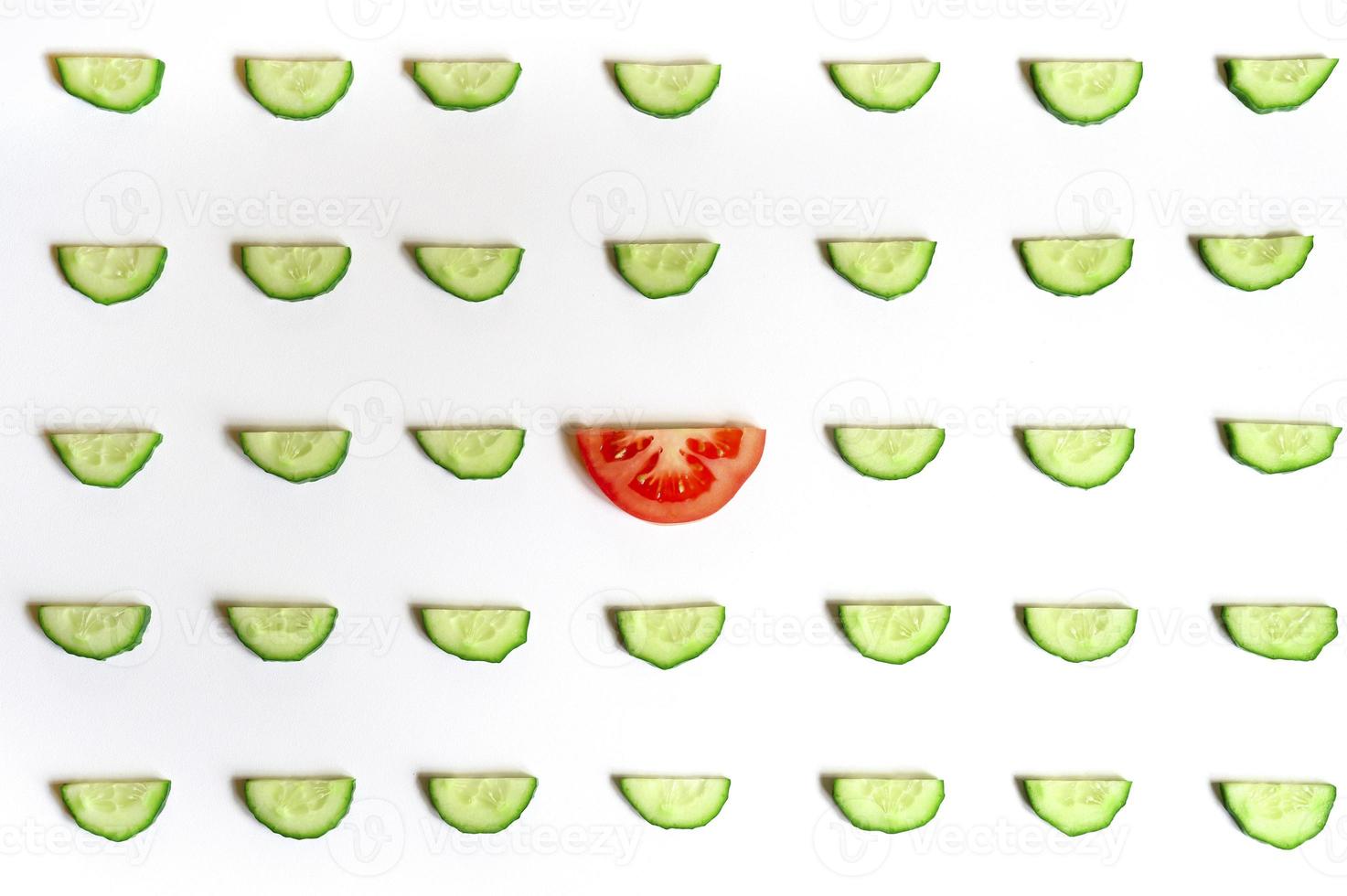 repeating pattern of sliced semicircles of fresh raw vegetable cucumbers for salad and a slice of tomato photo