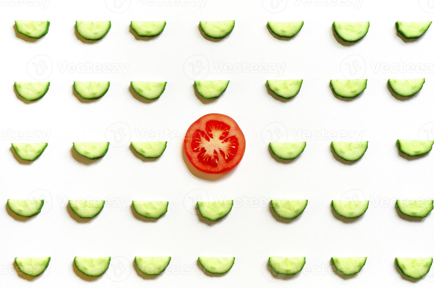 repeating pattern of sliced semicircles of fresh raw vegetable cucumbers for salad and a slice of tomato photo