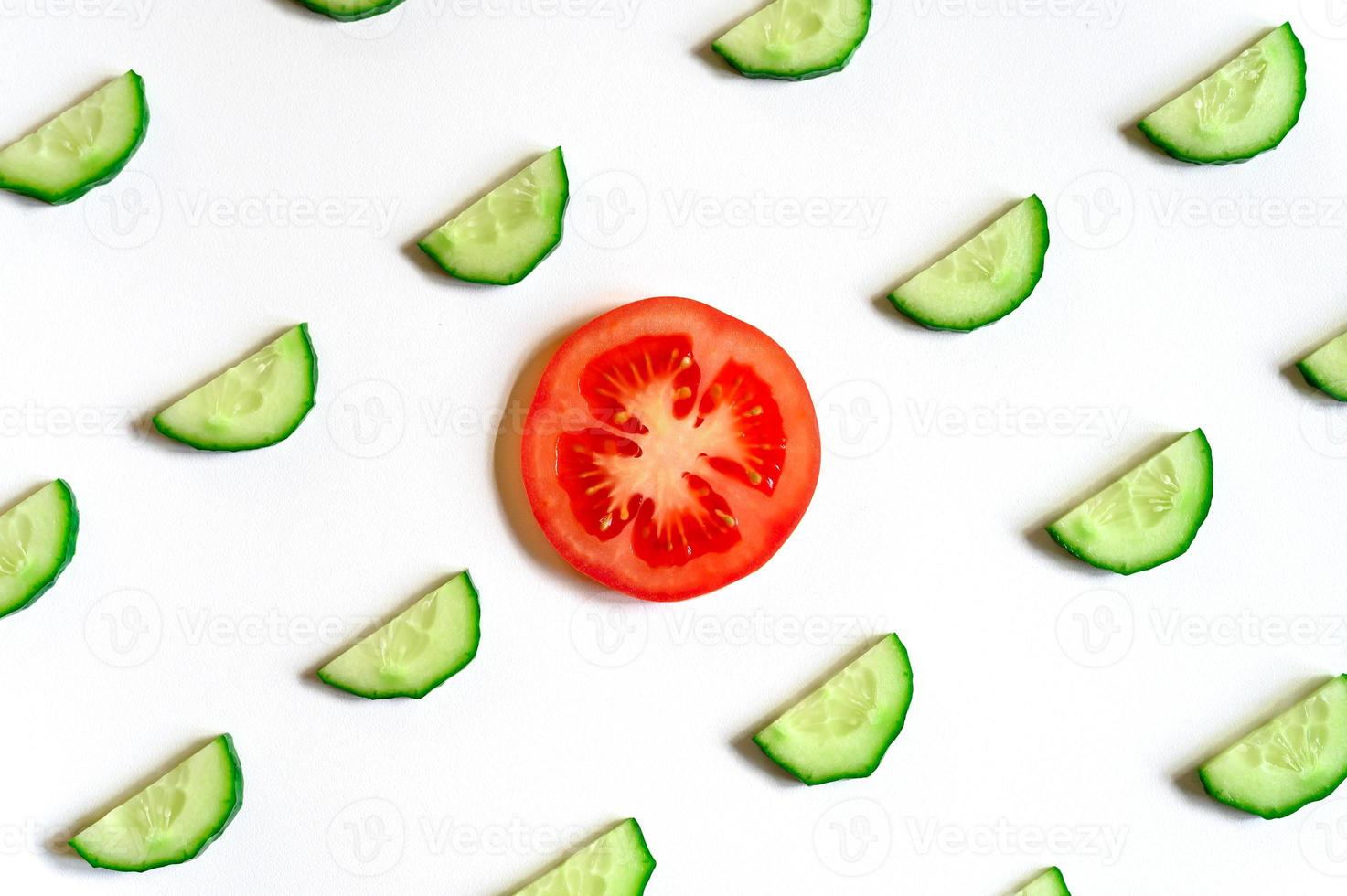 Patrón repetitivo de semicírculos en rodajas de pepinos vegetales crudos frescos para ensalada y una rodaja de tomate foto