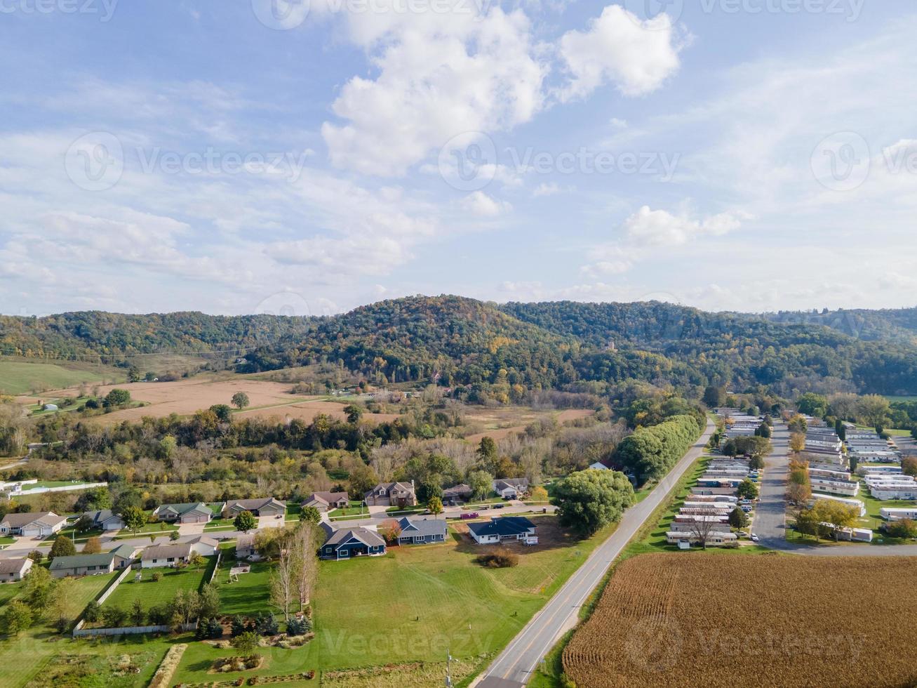 rural neighborhood and farm land in autumn in midwest mountains with trees and open landscape farm fields after harvest family friendly single-family homes and mobile home park for diversity. photo