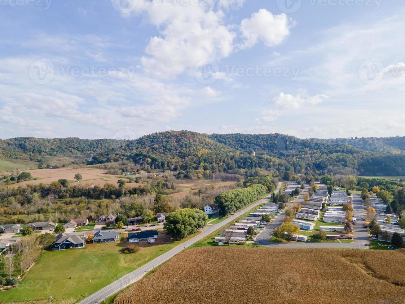 vecindario rural y tierras agrícolas en otoño en las montañas del medio oeste con árboles y campos agrícolas abiertos después de la cosecha Casas unifamiliares para familias y parque de casas móviles para la diversidad. foto