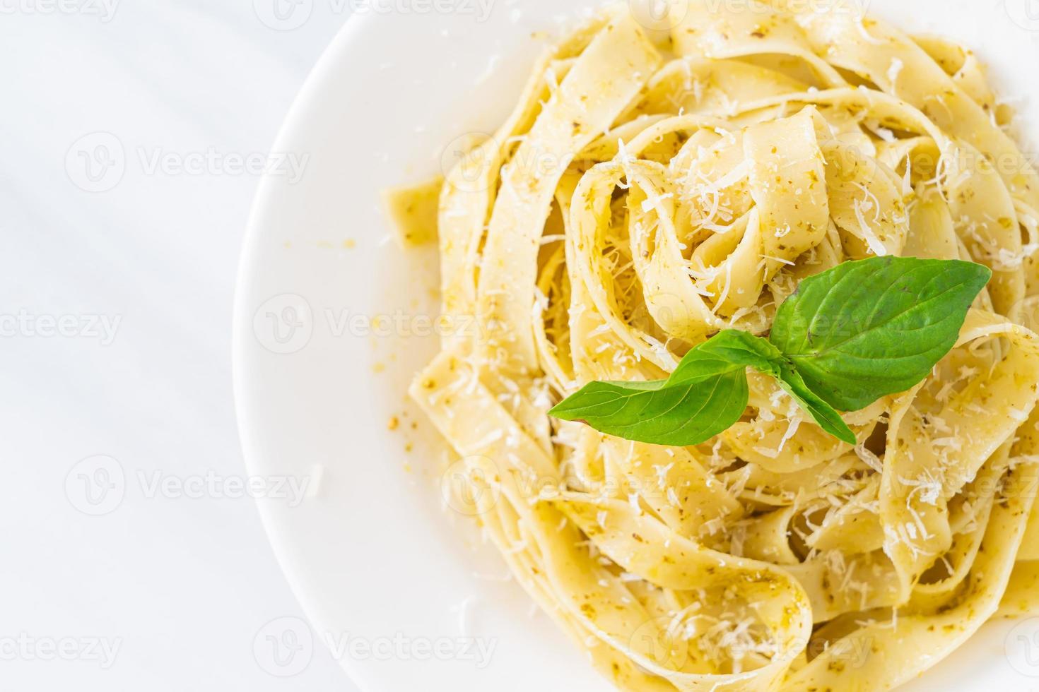 pesto fettuccine pasta with parmesan cheese on top photo