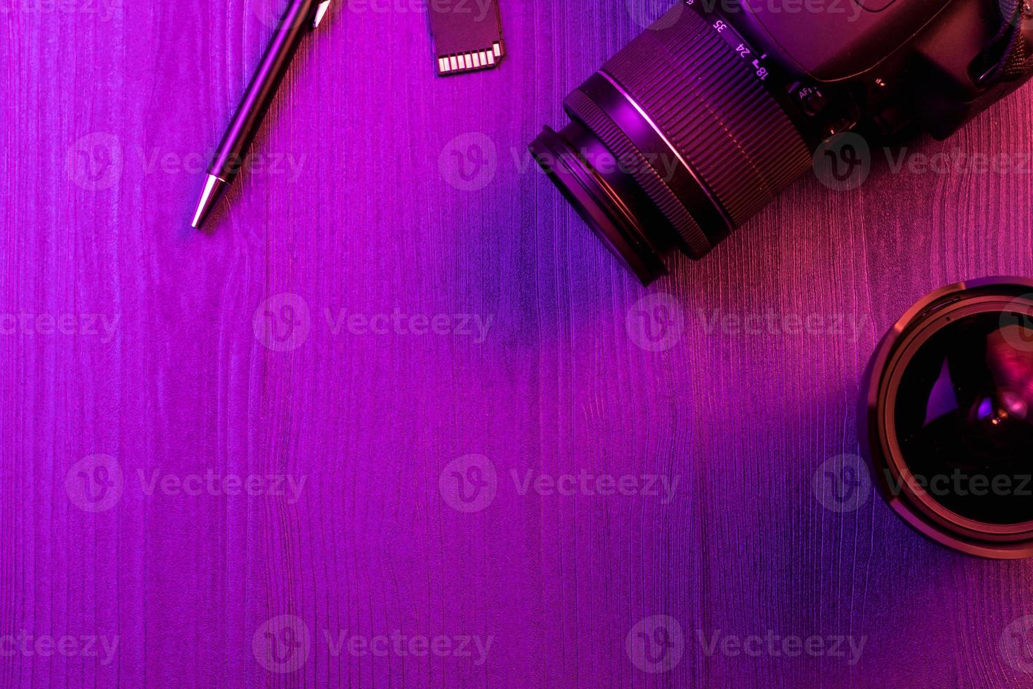 Camera, pencil, fish eye lens and SD card. Pink light. Workspace top view. Copy space. Wood background photo