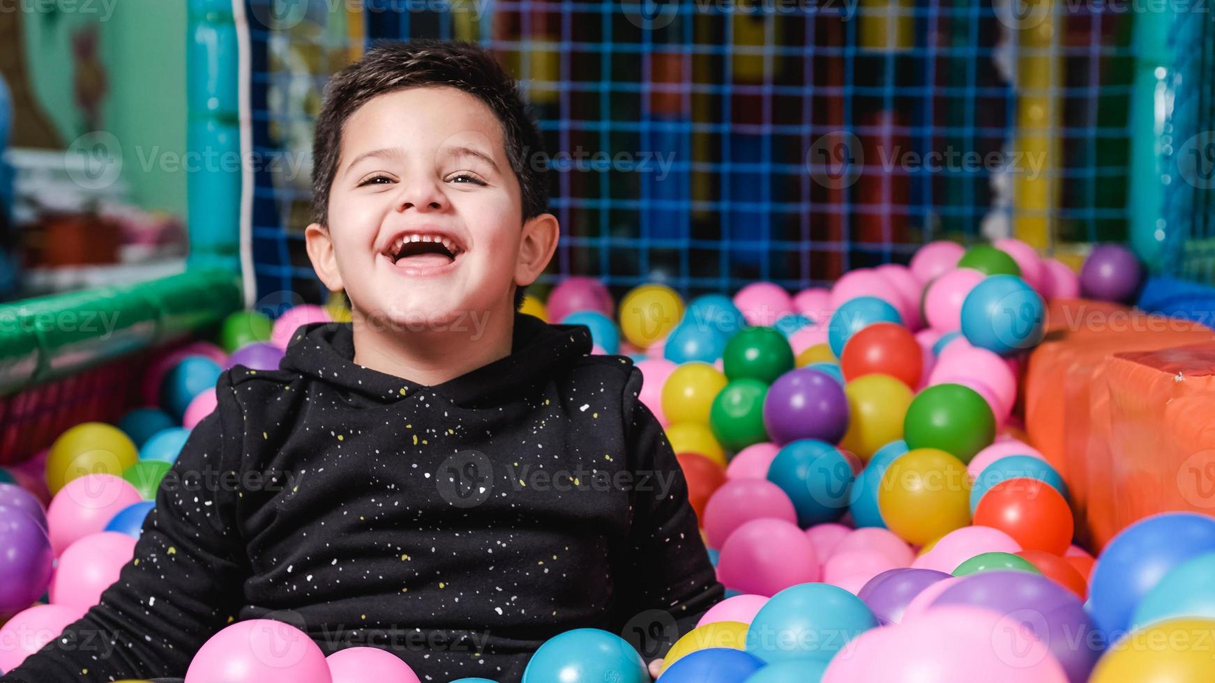 Feliz niño de 5 años con máscara en una piscina de bolas tan feliz foto