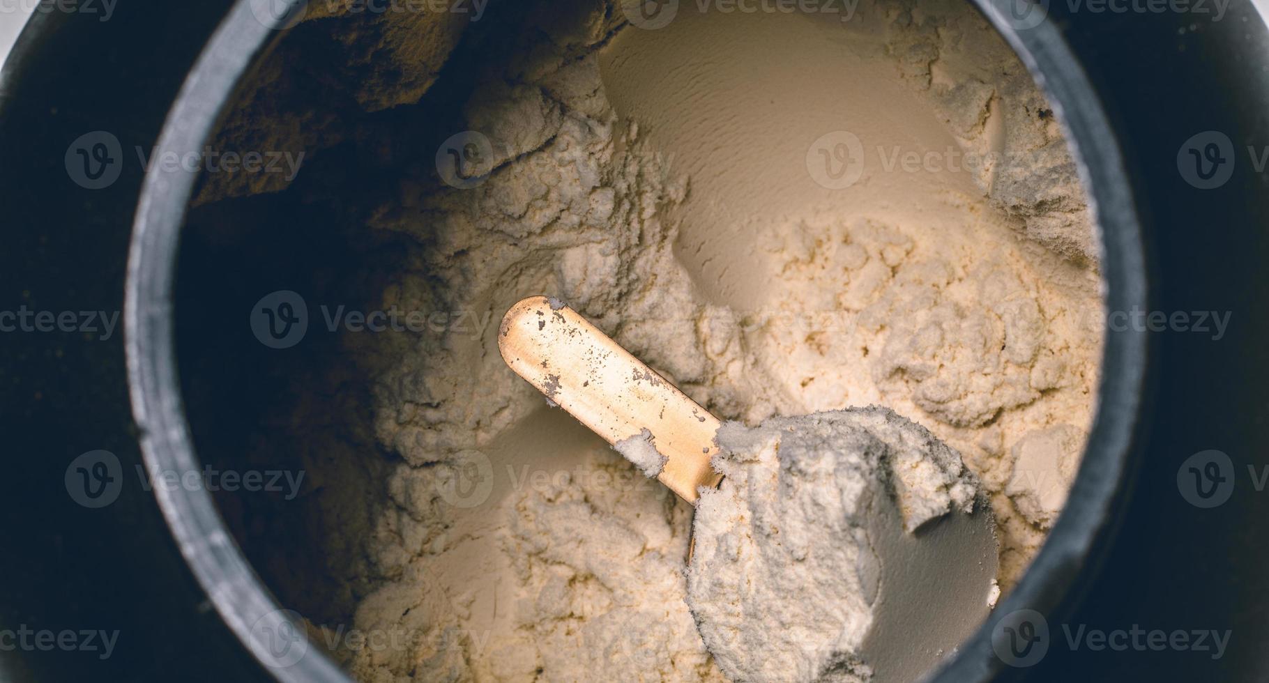 cucharadas llenas de proteína en polvo de vainilla en botella foto