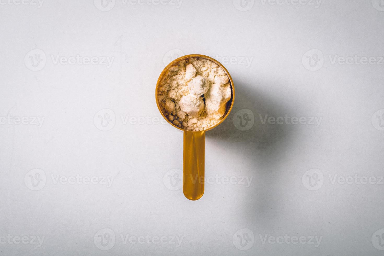 Scoops filled with protein vanilla powders on white background. top view with copy space for text. photo