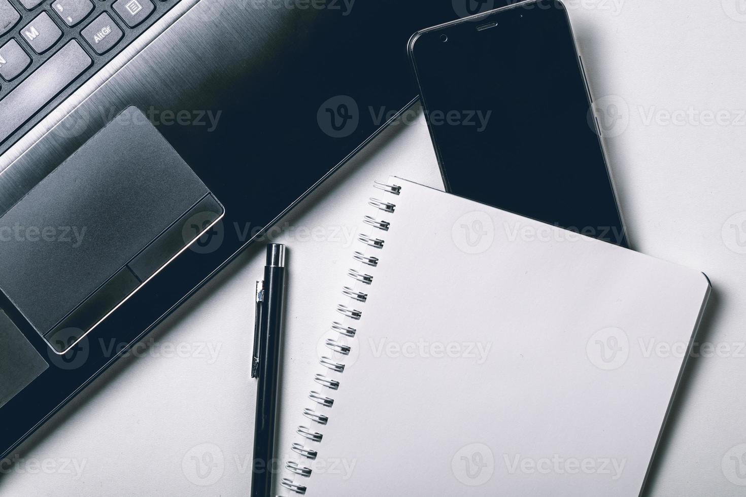 White office photography desk table with laptop, notebook, mobile phone and pen. Top view with copy space. Mock up photo