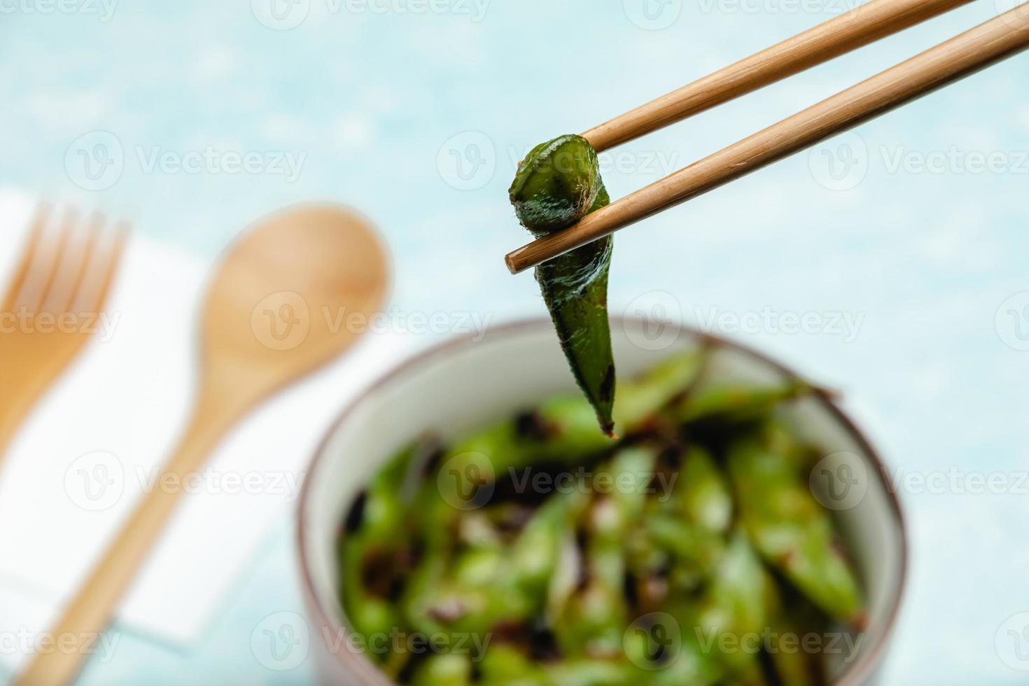 Cooked edamame on a blue tabletop. Snack soybean pods photo