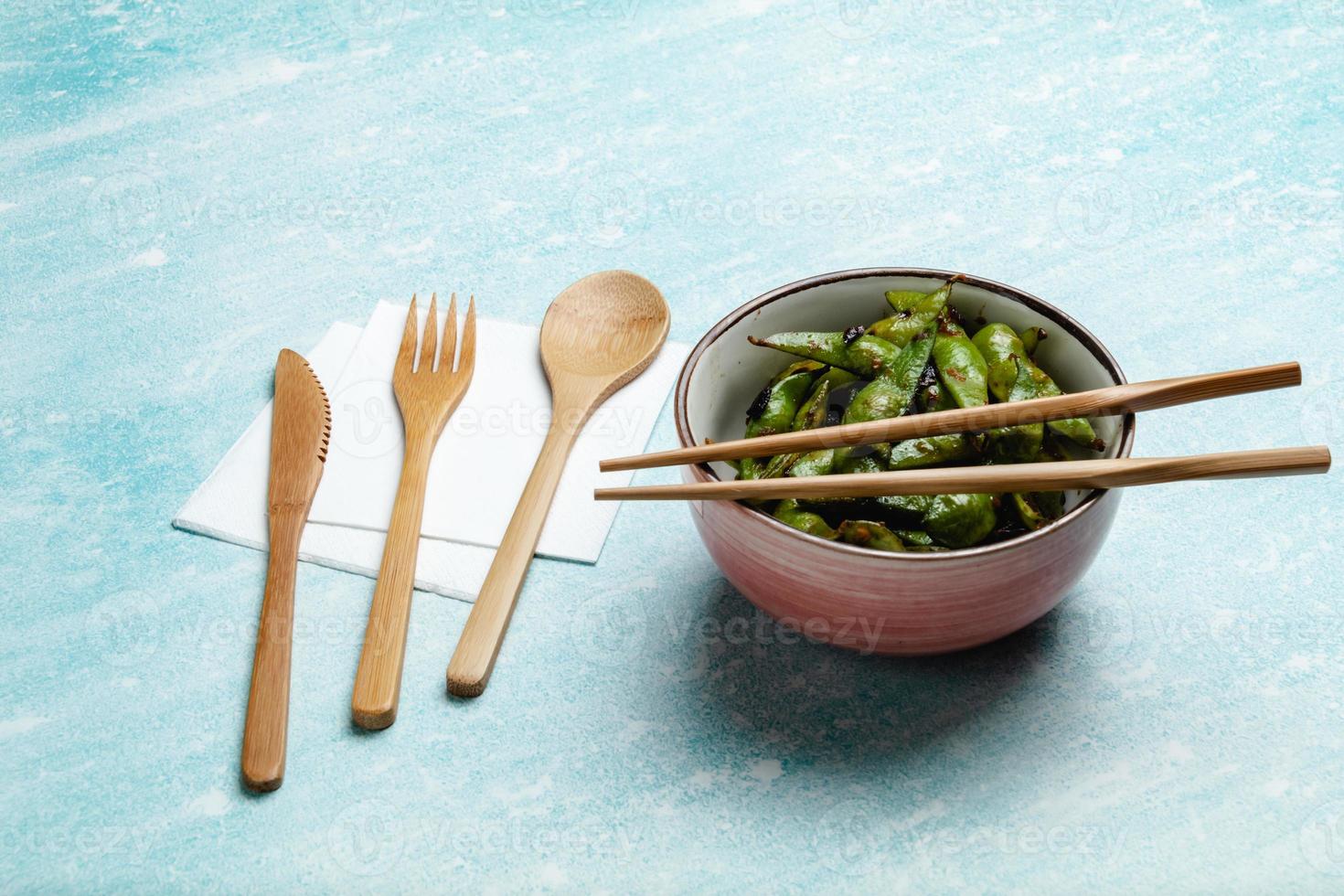 Cooked edamame on a blue tabletop. Snack soybean pods photo