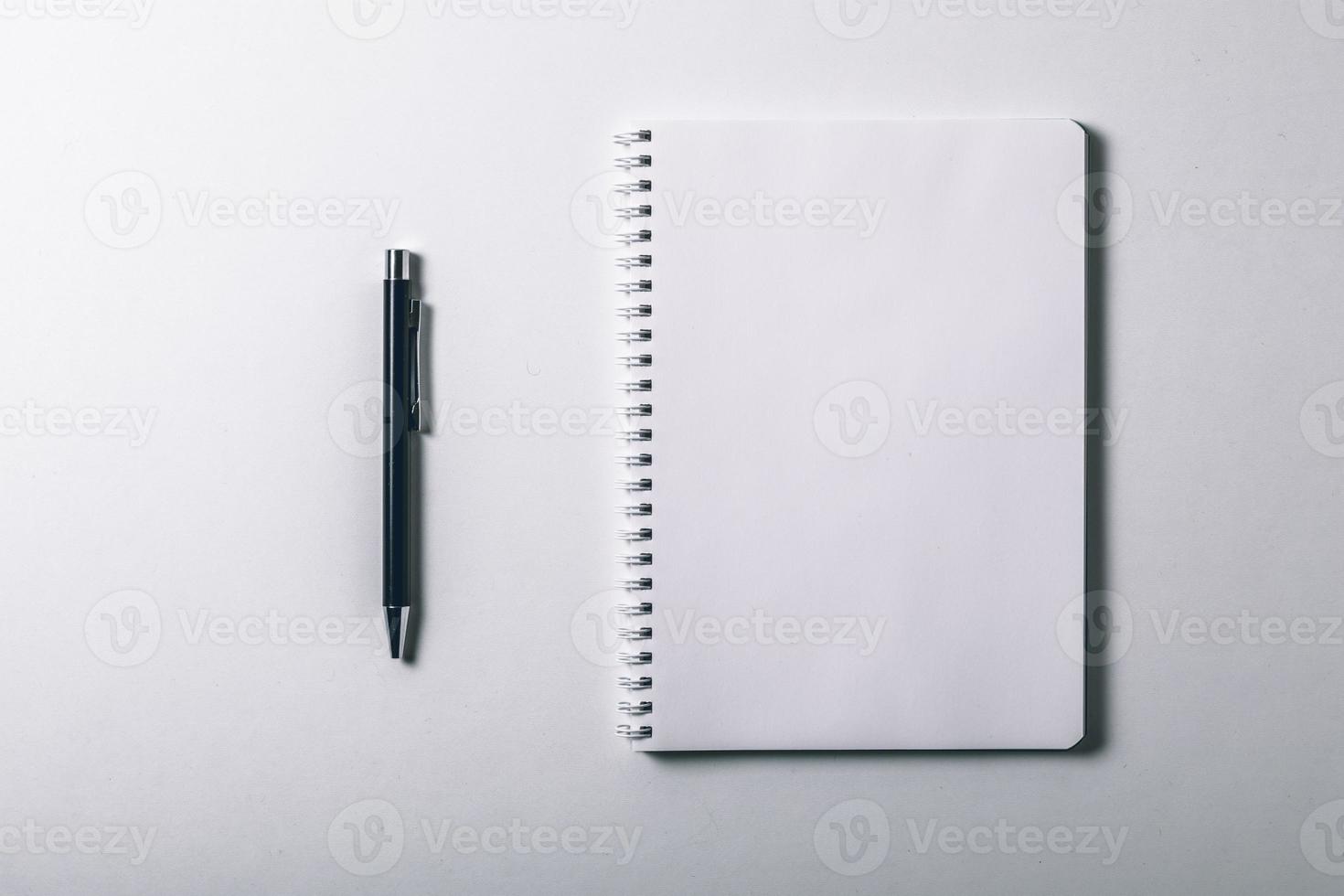 cuaderno y bolígrafo sobre fondo blanco. vista superior y espacio de copia. página de cuaderno en blanco para ingresar el texto en el medio foto