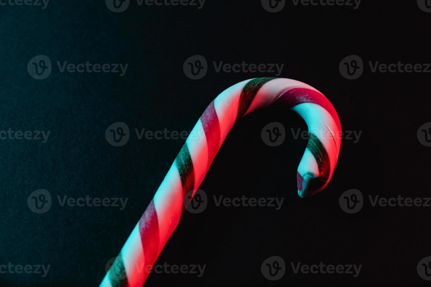 Minimal Christmas composition. Greeting card template with candy cane on dark background. photo
