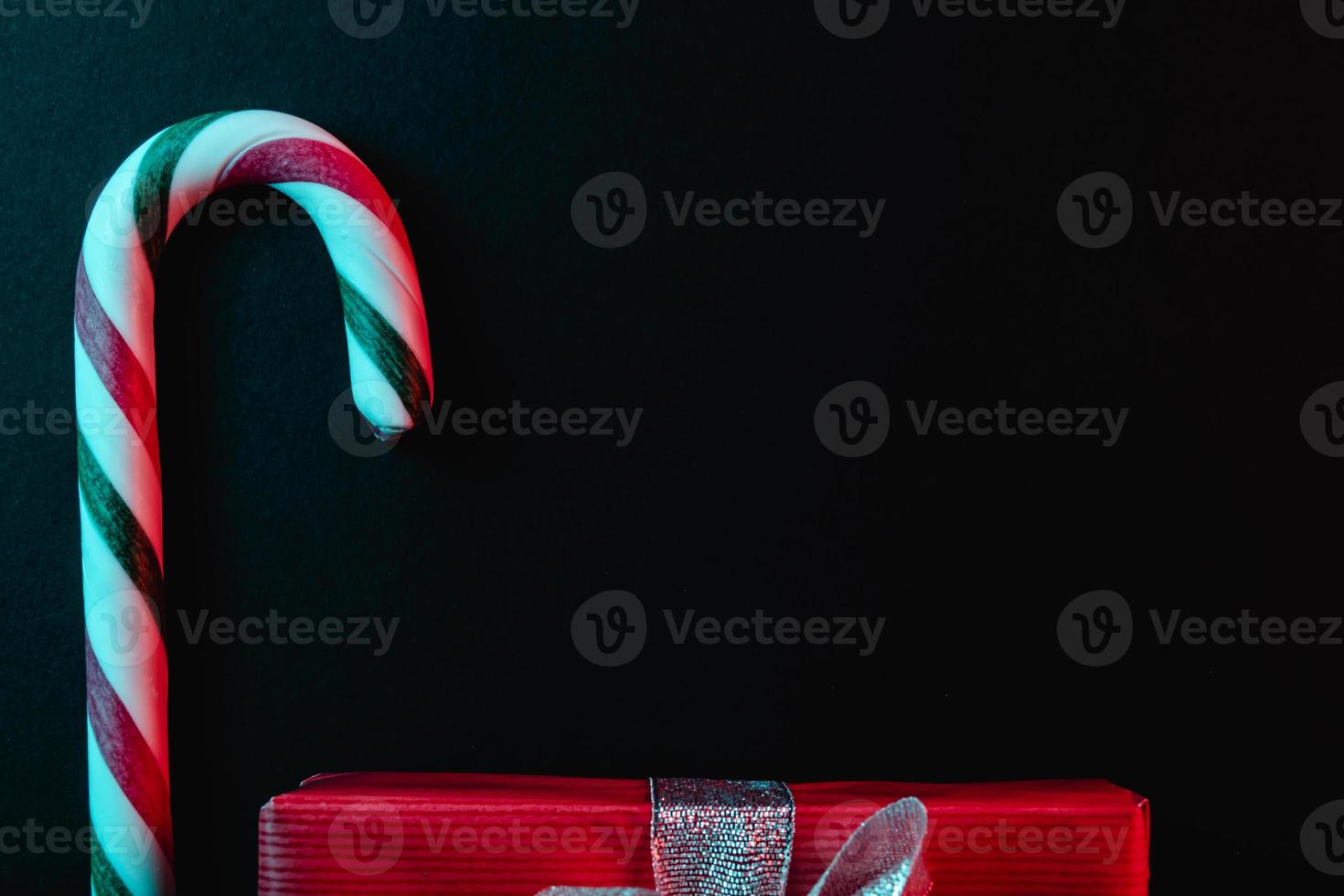 Minimal Christmas composition. Greeting card template with candy cane on dark background. photo