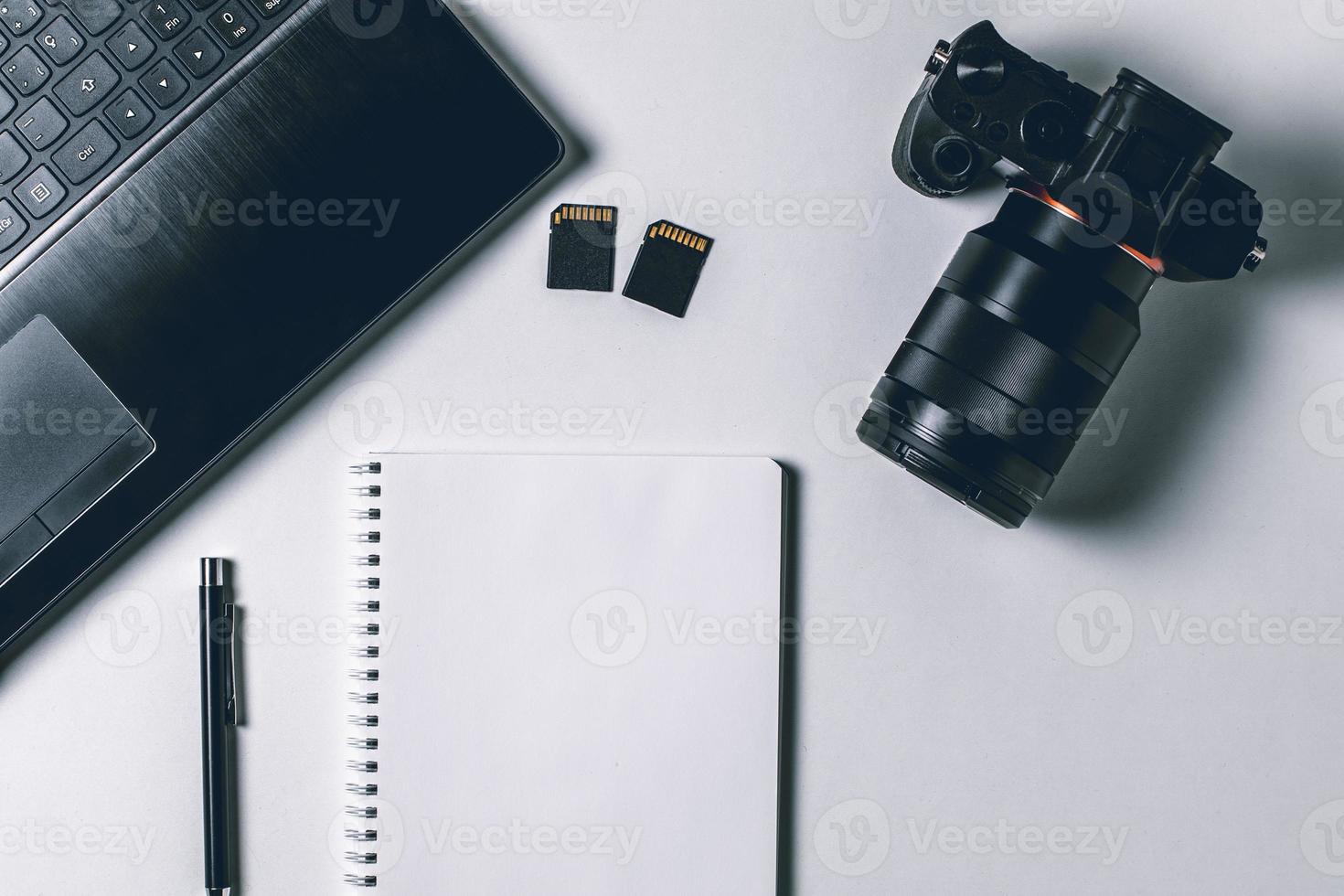 White office photography desk table with laptop, notebook, camera and pen. Top view with copy space. Mock up photo