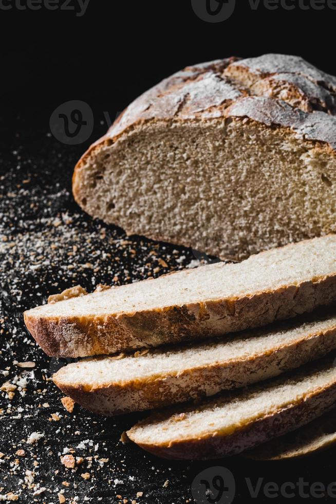 Sliced loaf of dark homemade bread dusted with flour photo
