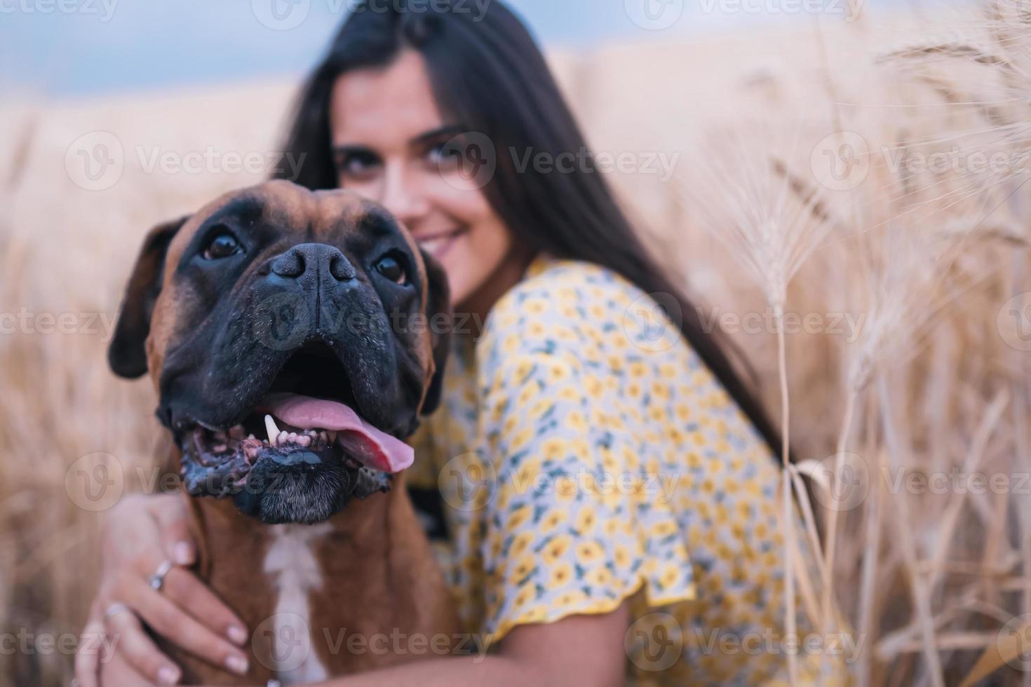 Vista de cerca de una joven mujer feliz abrazando a su perro en medio de un campo de trigo. concepto de naturaleza y animales. foto