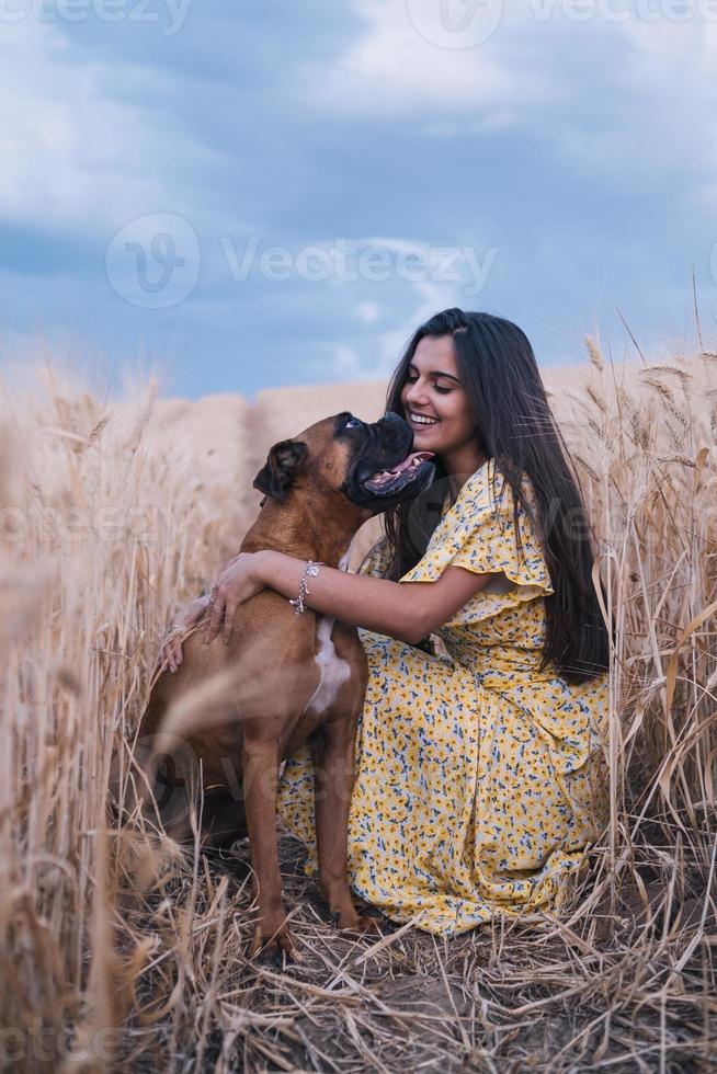 Retrato de una joven alegre divirtiéndose y disfrutando de la naturaleza con su perro en un campo de trigo. foto