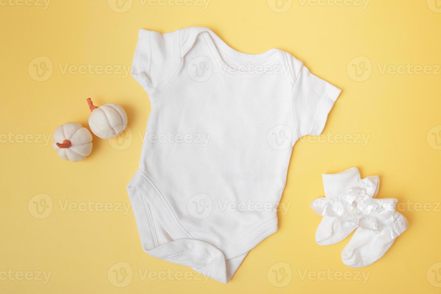 Baby clobodysuit mock-up with pumpkins on yellow background for your text or logo place in autumn season photo