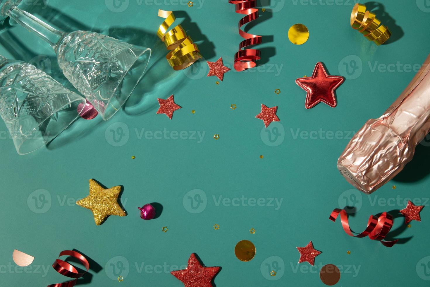 Christmas new year flat lay with champagne, glass and  stars, streamers and copy space on green background photo