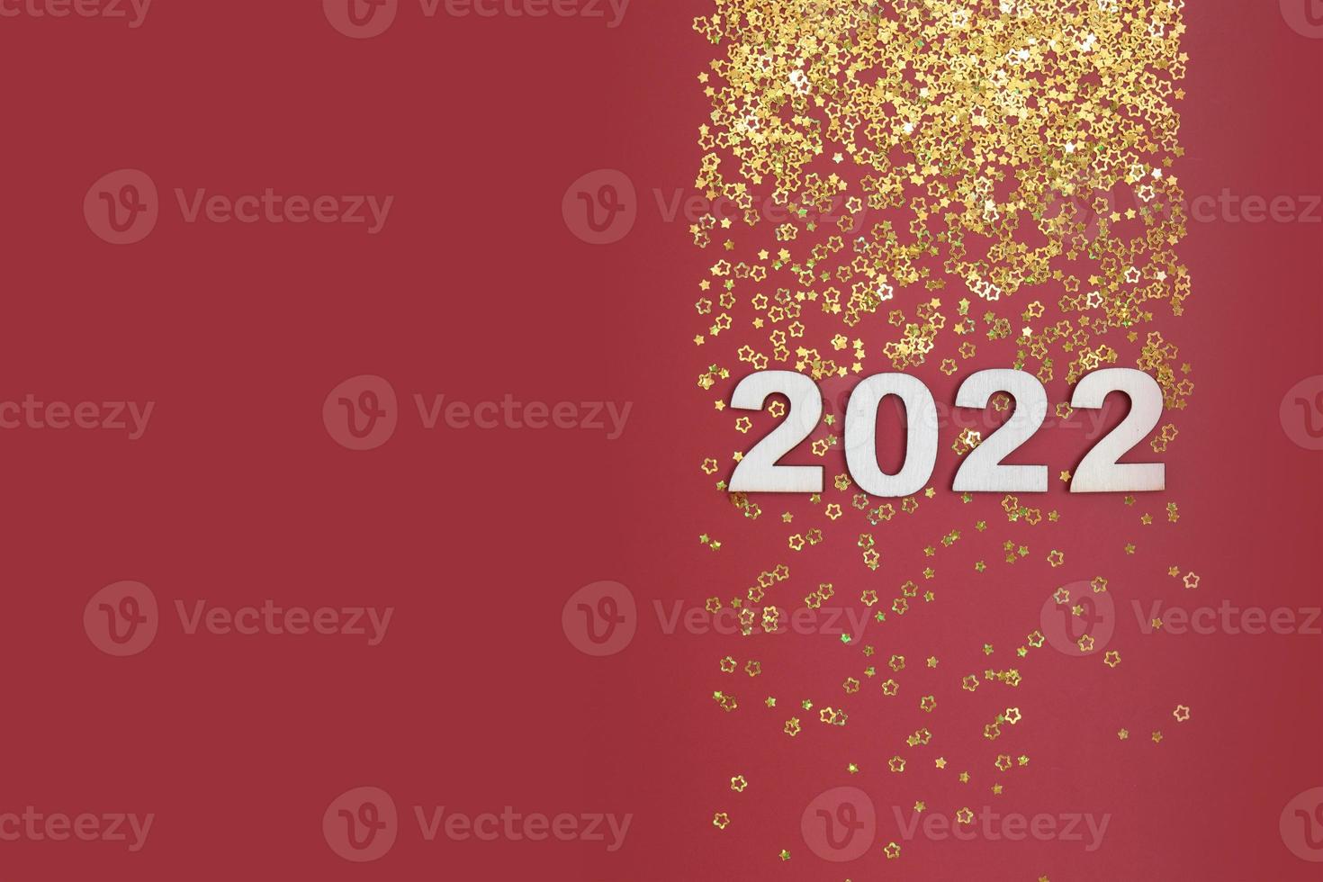 New year 2022 numbers on red background with golden stars copy space photo