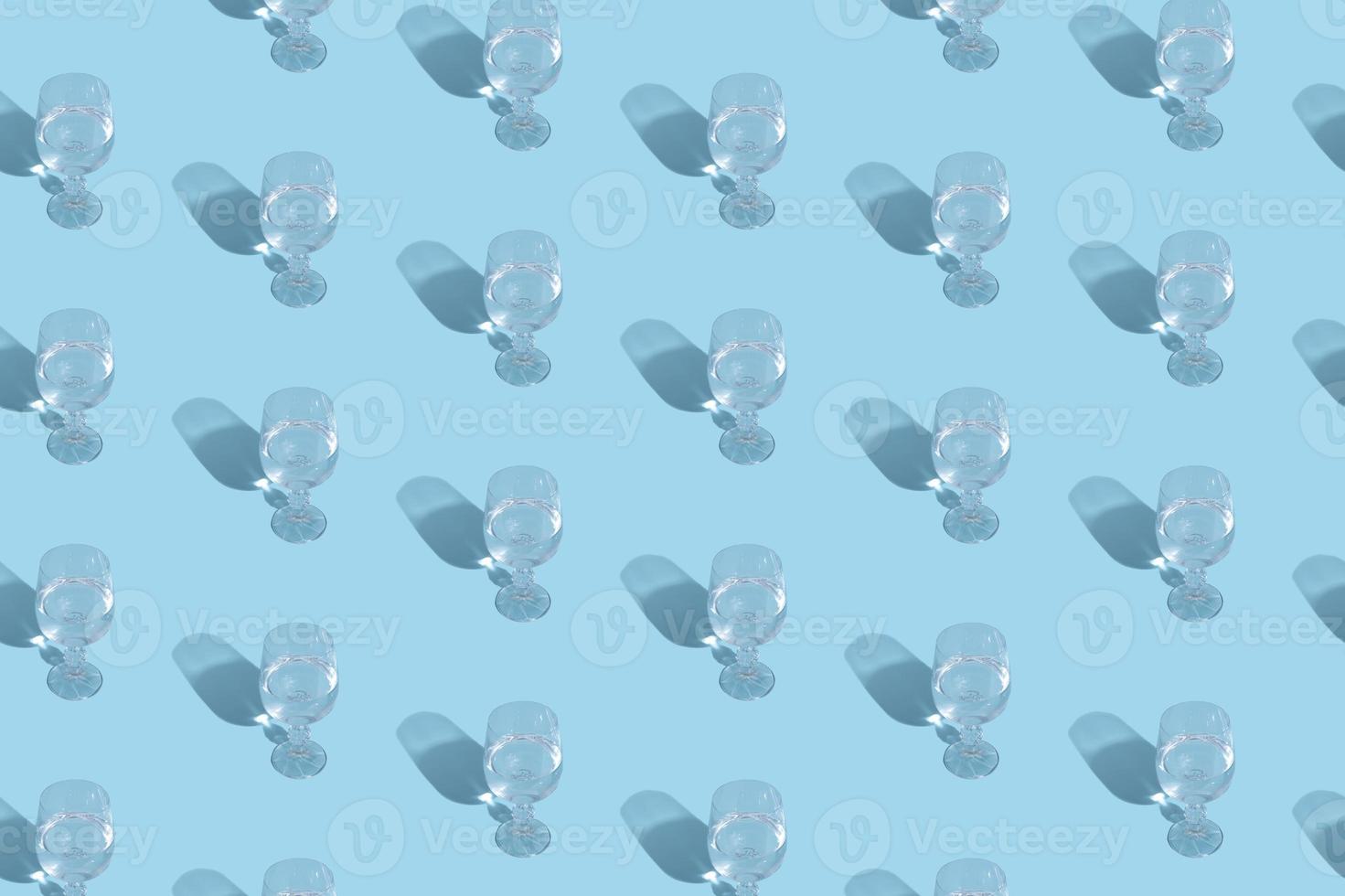 Glass with water and shadow pattern on blue background photo