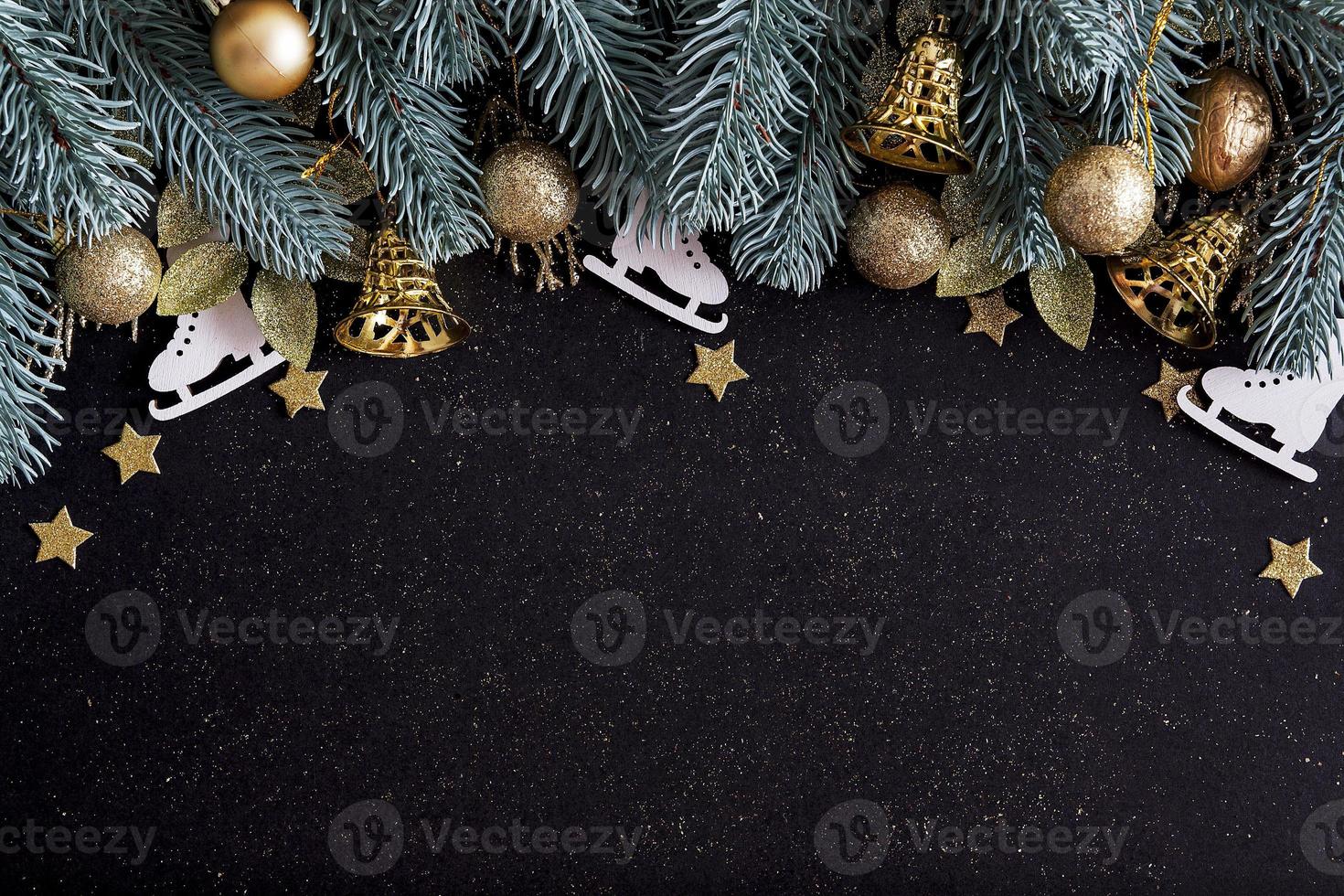 Top view Merry Christmas black background decorated with Happy New Year Christmas tree branches, stars, bells and baubles with copy space. Winter holiday card decoration festive fun concept, flat lay. photo