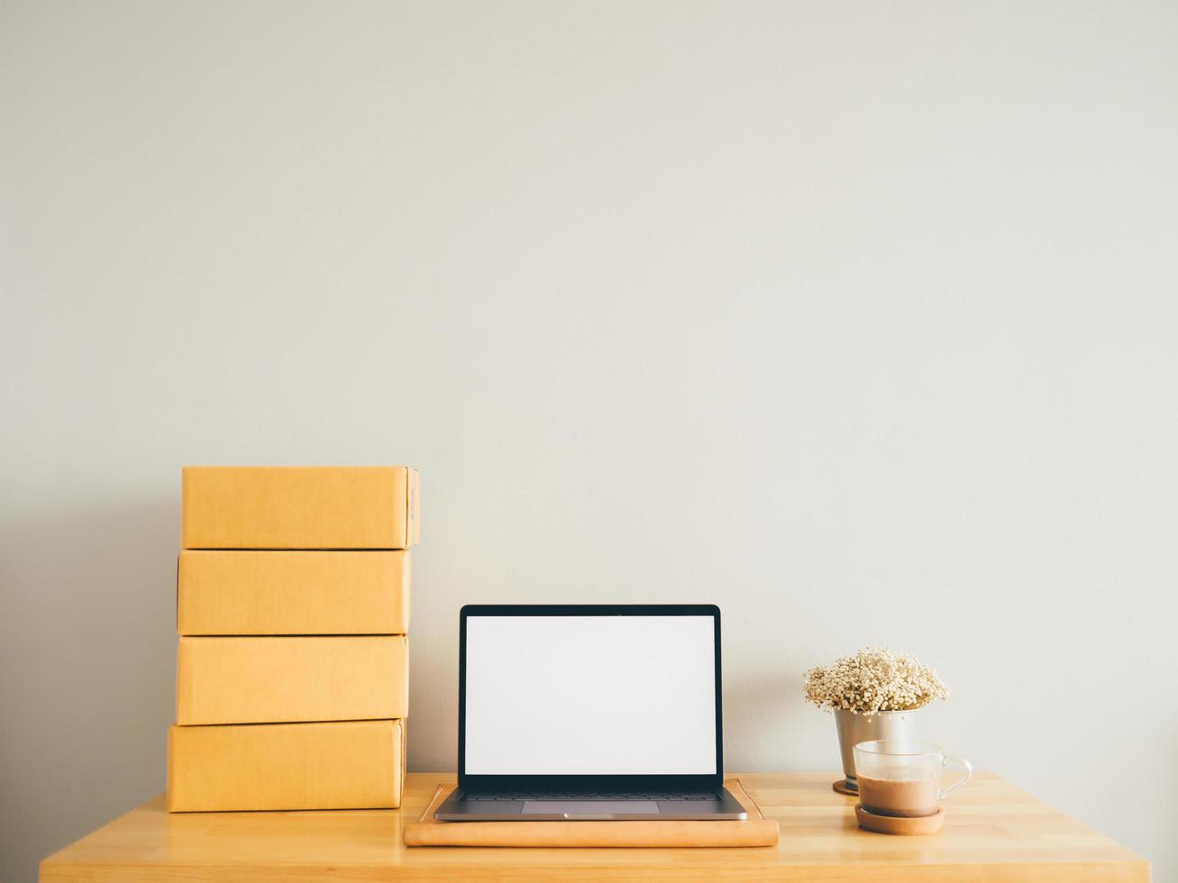 Mockup of white empty display laptop with boxes on table. Concept of online business. photo