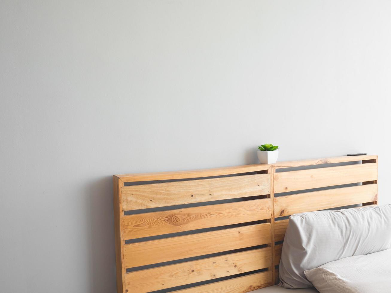 Wooden board of top bed with pot plant and wall. photo